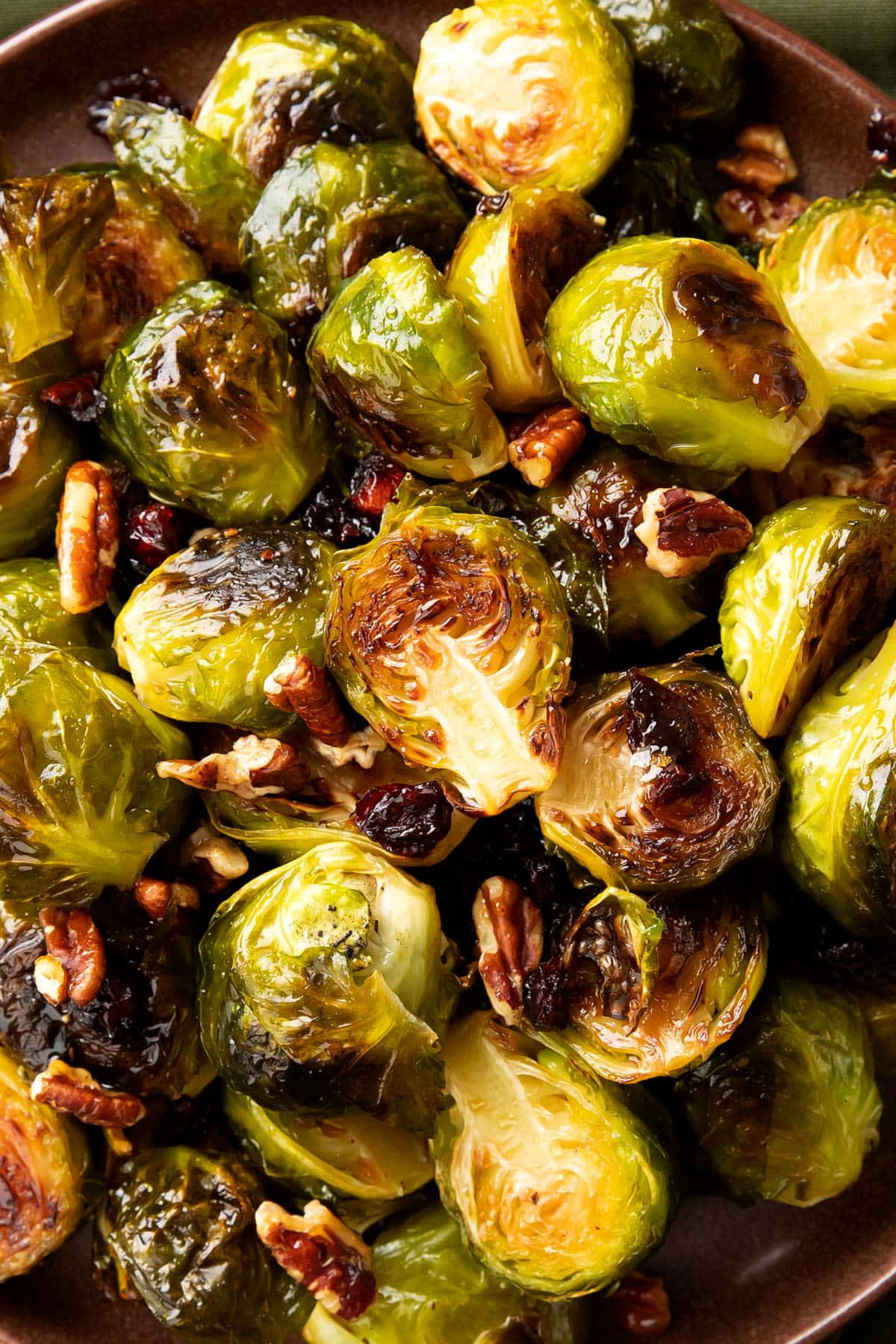 Close up of maple glazed brussel sprouts recipe shows crisped edges, sweet glaze, and delicious add-ins like bacon sprinkled on top.