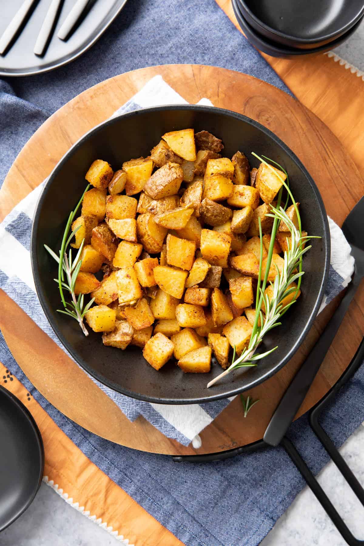 Crispy breakfast potatoes served with rosemary on a dining table