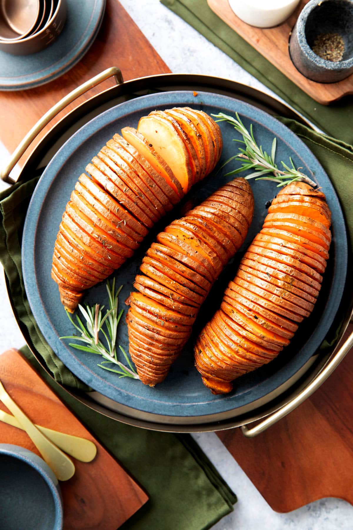 a holiday table set for dinner with Hasselback sweet potatoes just baked and coated with herbs and butter