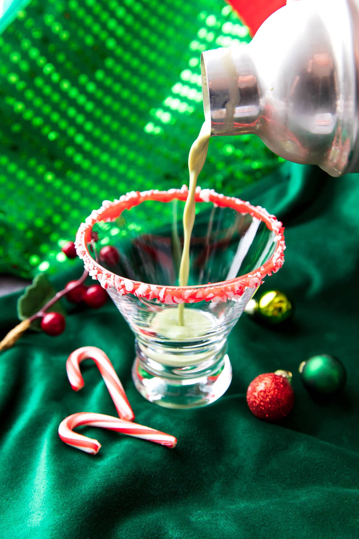 Someone pouring a peppermint martini mixture into a martini glass.