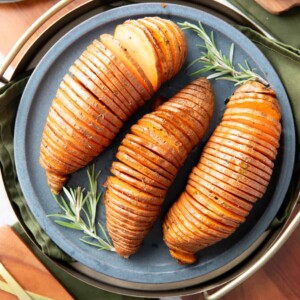 square photo of hasselback sweet potatoes on a blue plate