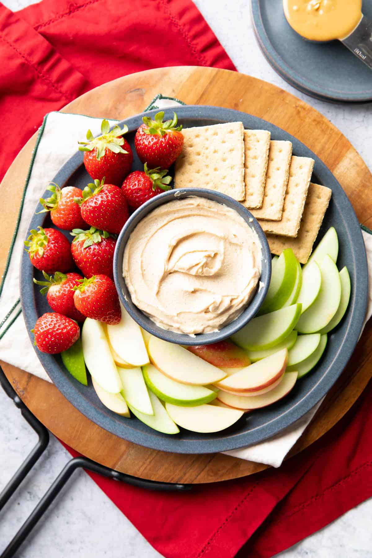 peanut butter dip in a blue bowl on top of a wooden tray