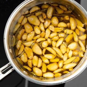 square photo of garlic confit in a pan