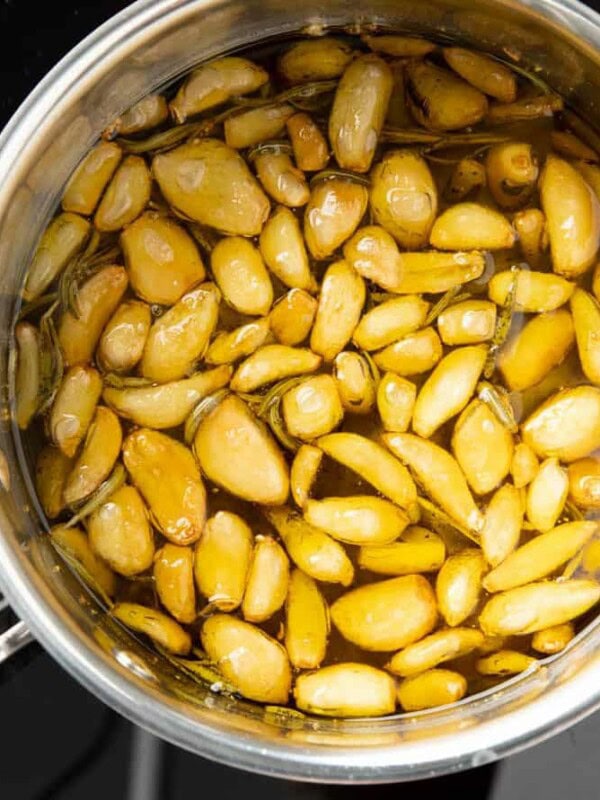 square photo of garlic confit in a pan