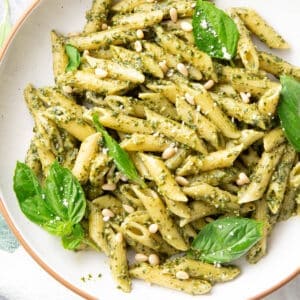 a bowl of pesto pasta topped with basil