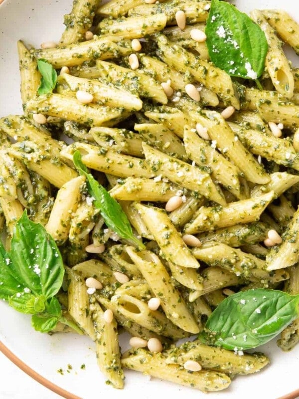 a bowl of pesto pasta topped with basil