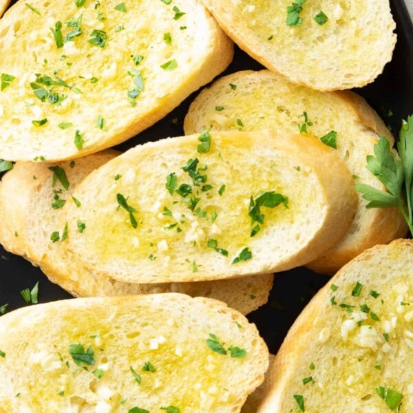 closeup photo of garnish and oil on baked garlic toast