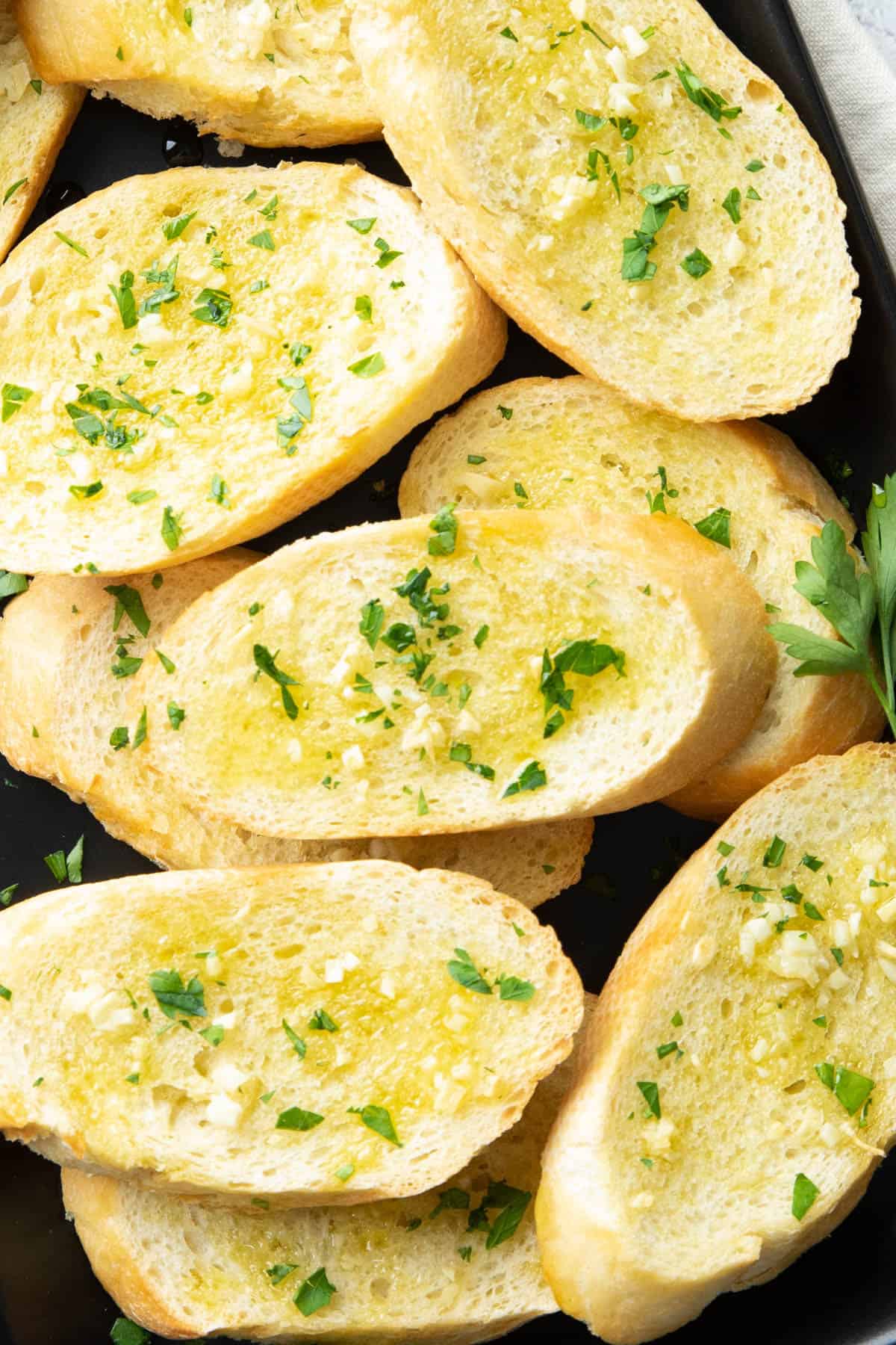 closeup photo of garnish and oil on baked garlic toast