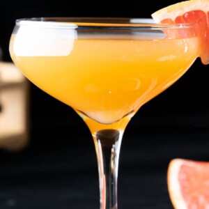 close up of a brown derby cocktail served in a coupe glass with a grapefruit garnish