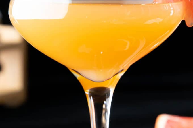 close up of a brown derby cocktail served in a coupe glass with a grapefruit garnish