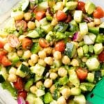 close up of chickpea salad showing chickpeas, cucumbers, tomatoes, and creamy salad dressing