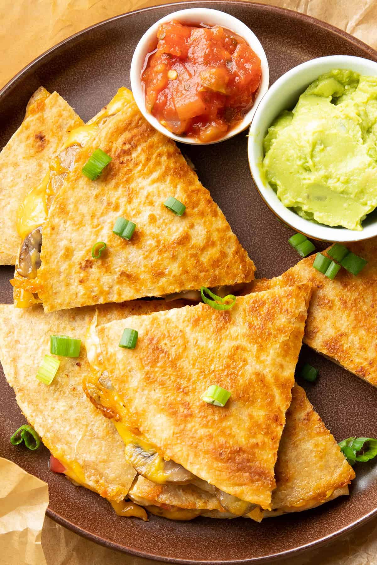 photo showing the crisp golden texture of the finished recipe with green onions, salsa, and guacamole