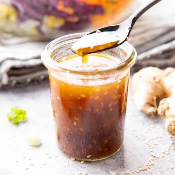 Jar of asian salad dressing with sesame seeds floating in it