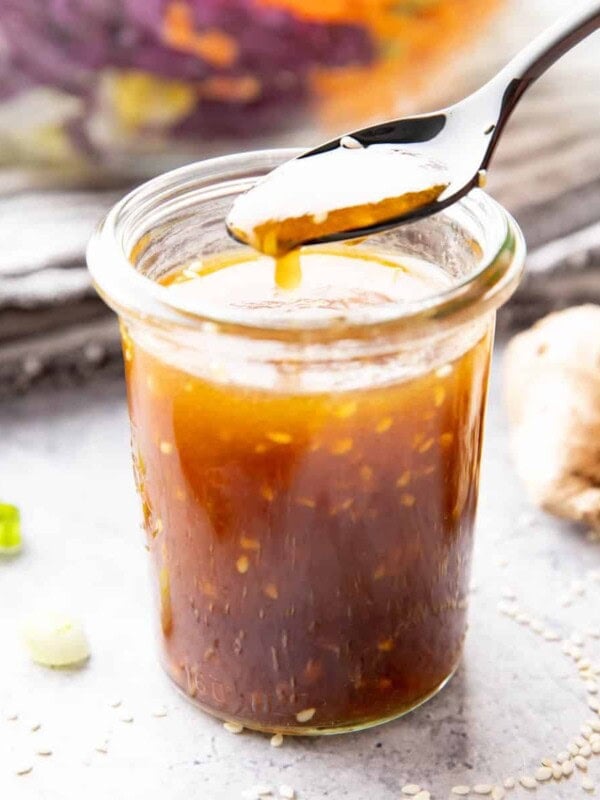 Jar of asian salad dressing with sesame seeds floating in it