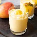 Pineapple Mango Smoothie in a glass with fruit garnish