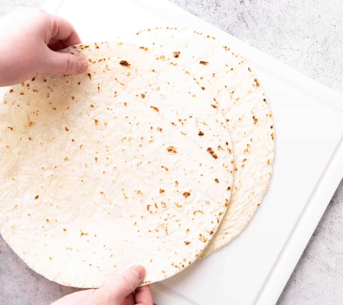 Photo showing How to Make Baked Tortilla Chips – stacking tortillas on a cutting board