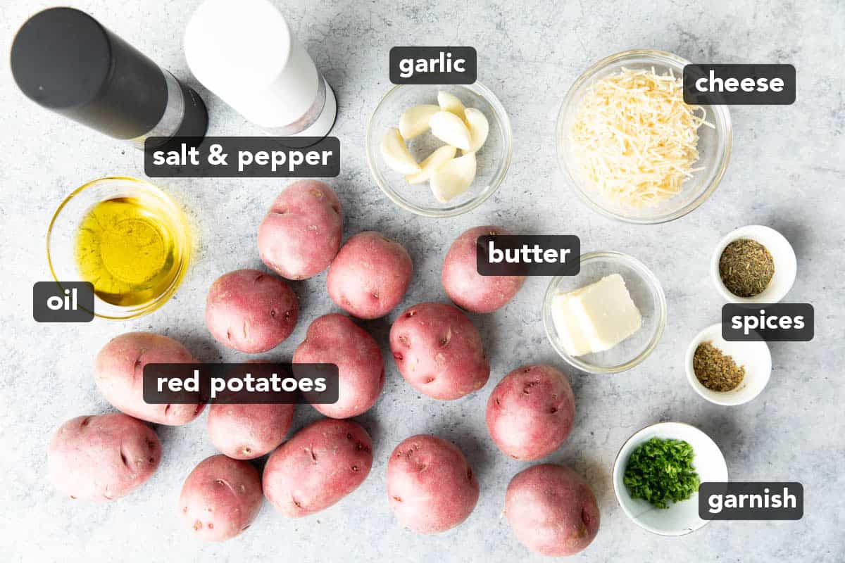 roasted garlic potatoes ingredients laid out on a kitchen table, including butter, red potatoes, parsley, and more