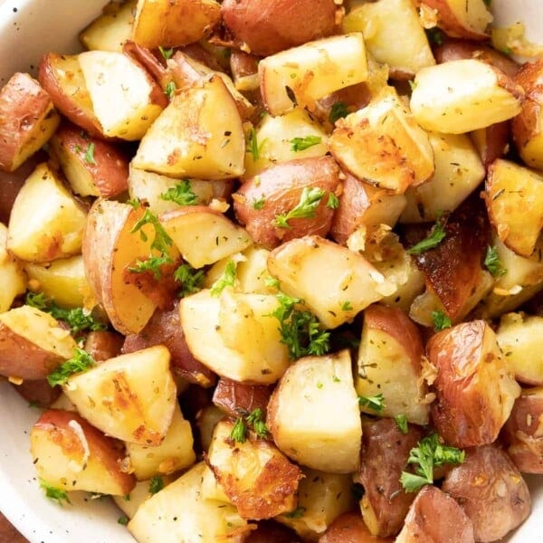 Close up of garlic parmesan roasted potatoes in a serving bowl.