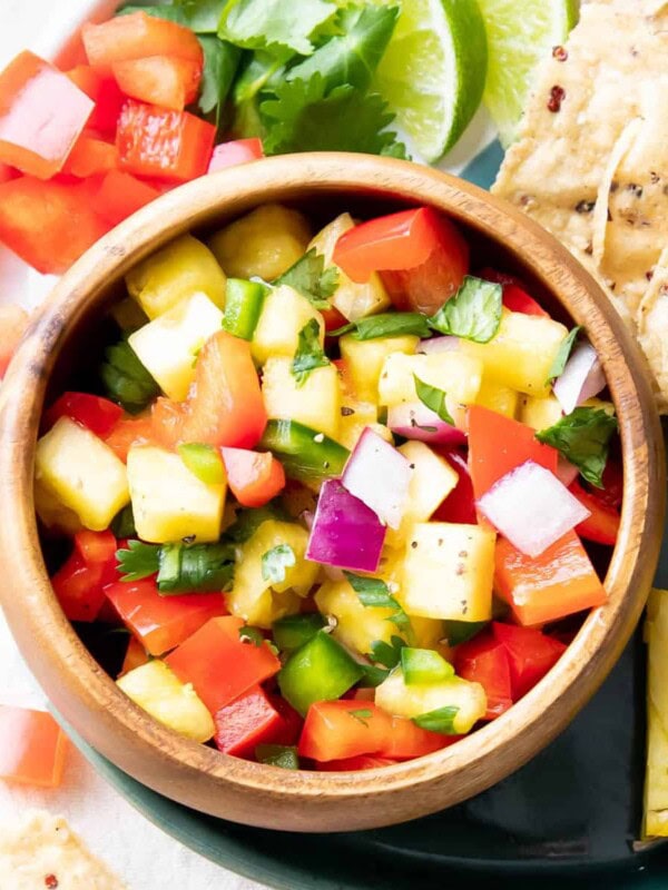 Dipping bowl filled with pineapple salsa served with tortilla chips and lime wedges