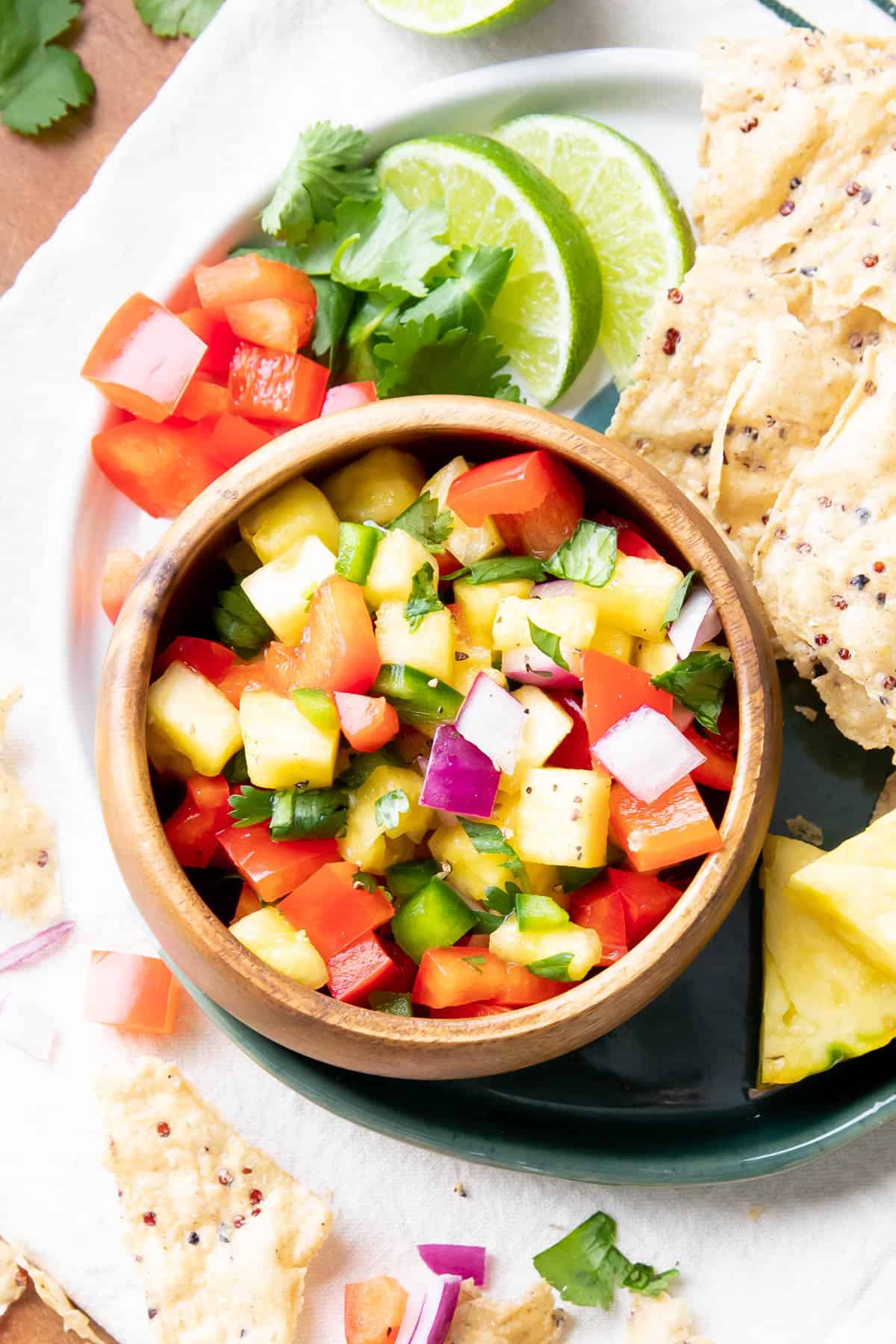 Pineapple Salsa in a wooden serving bowl with limes