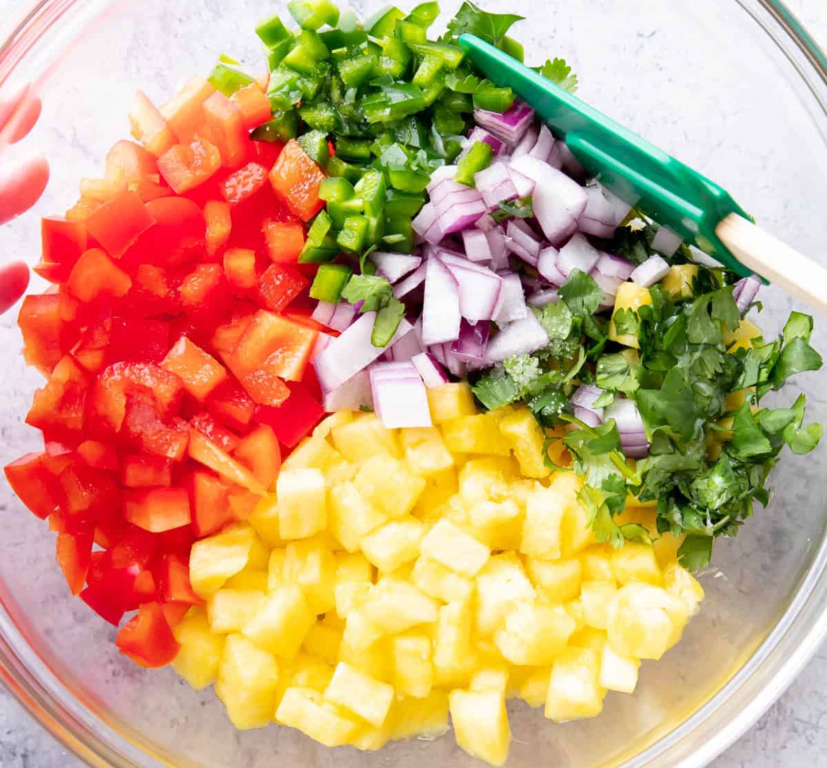 Hand holding a green spatula stirring ingredients together