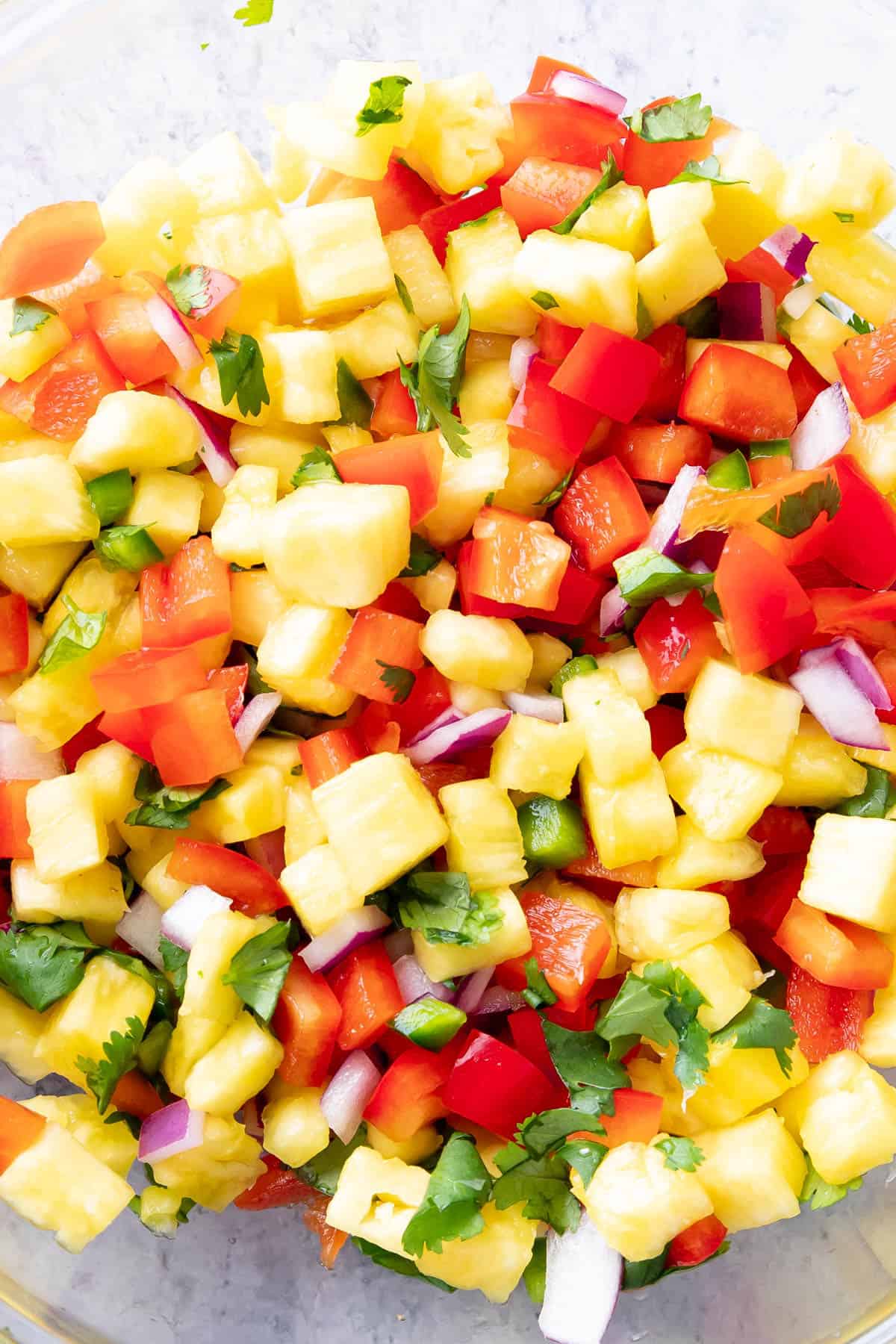 close up of chopped bell peppers, onions, cilantro, and lime juice in a mixing bowl