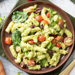Pesto pasta salad served with tomatoes on a brown plate