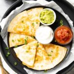 perfectly crisped cheese quesadilla served with sour cream and guacamole
