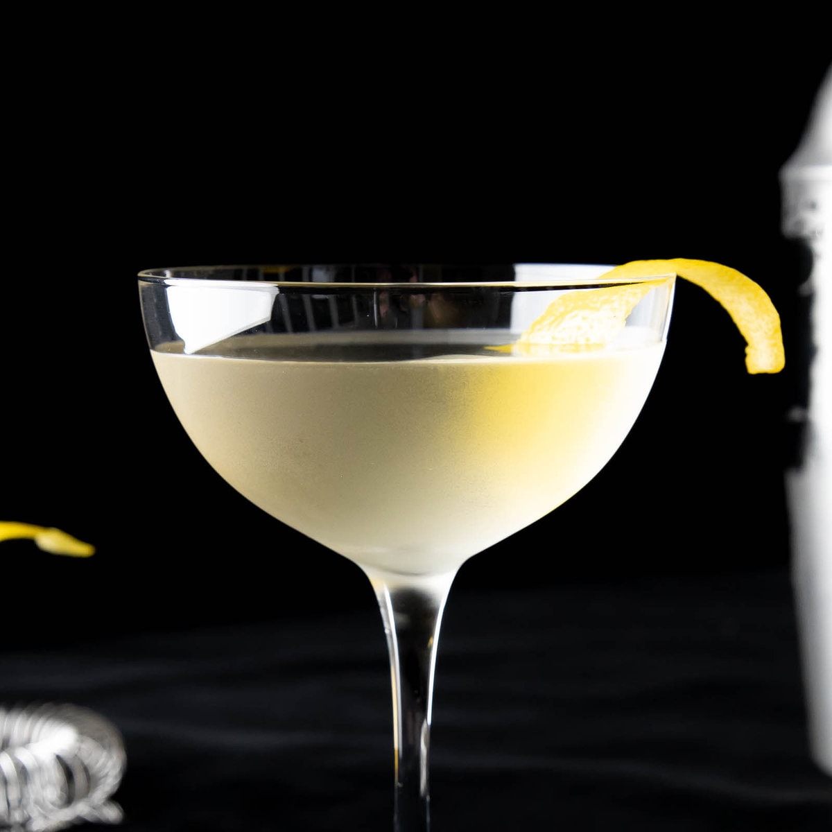 50/50 martini served in a coupe glass with a lemon garnish on a black backdrop