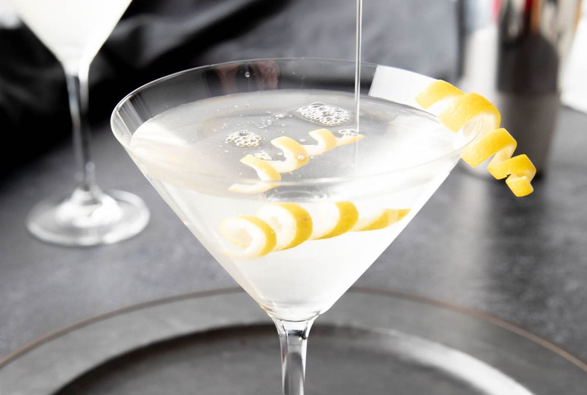 Pouring martini mixture from a cocktail shaker into a martini glass