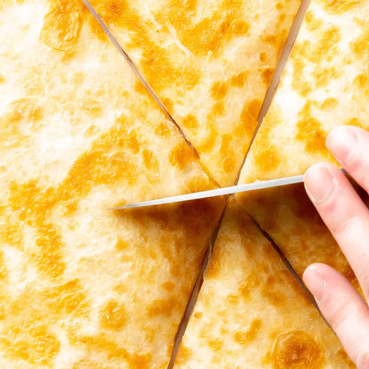 super close up of hand holding a knife slicing this Mexican-inspired dish