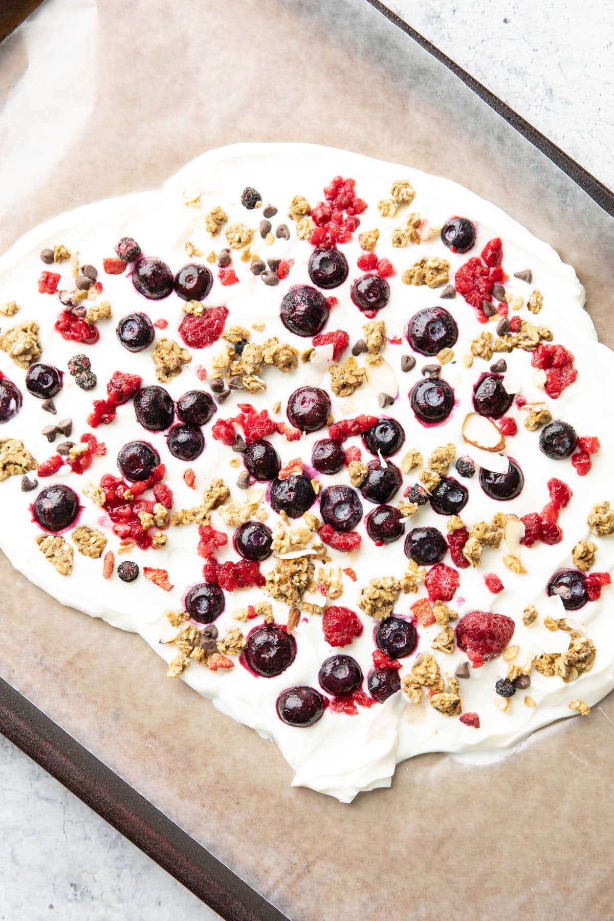 Close up photo of blueberries, raspberries, granola, and chocolate chip topping spread across the top of each bar