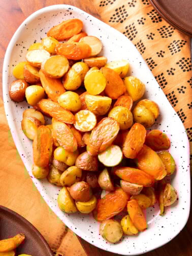 Roasted carrots and potatoes are oven-roasted until tender and served on a Thanksgiving table