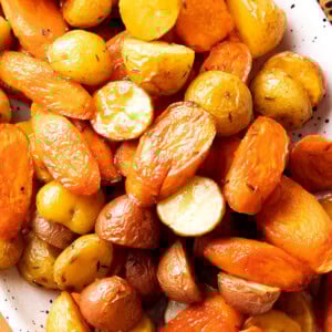 close up of roasted carrots and potatoes to show butter, herbs, and other seasonings that coat this recipe