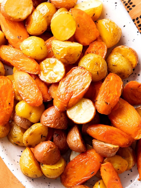 close up of roasted carrots and potatoes to show butter, herbs, and other seasonings that coat this recipe
