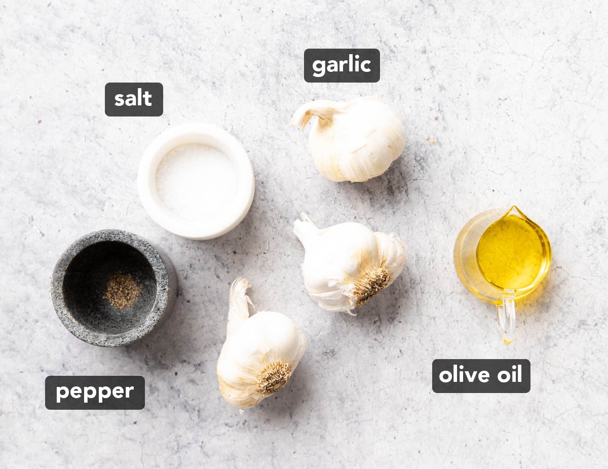 składniki pieczonego czosnku, w tym główki czosnku, oliwa z oliwek, sól i pieprz