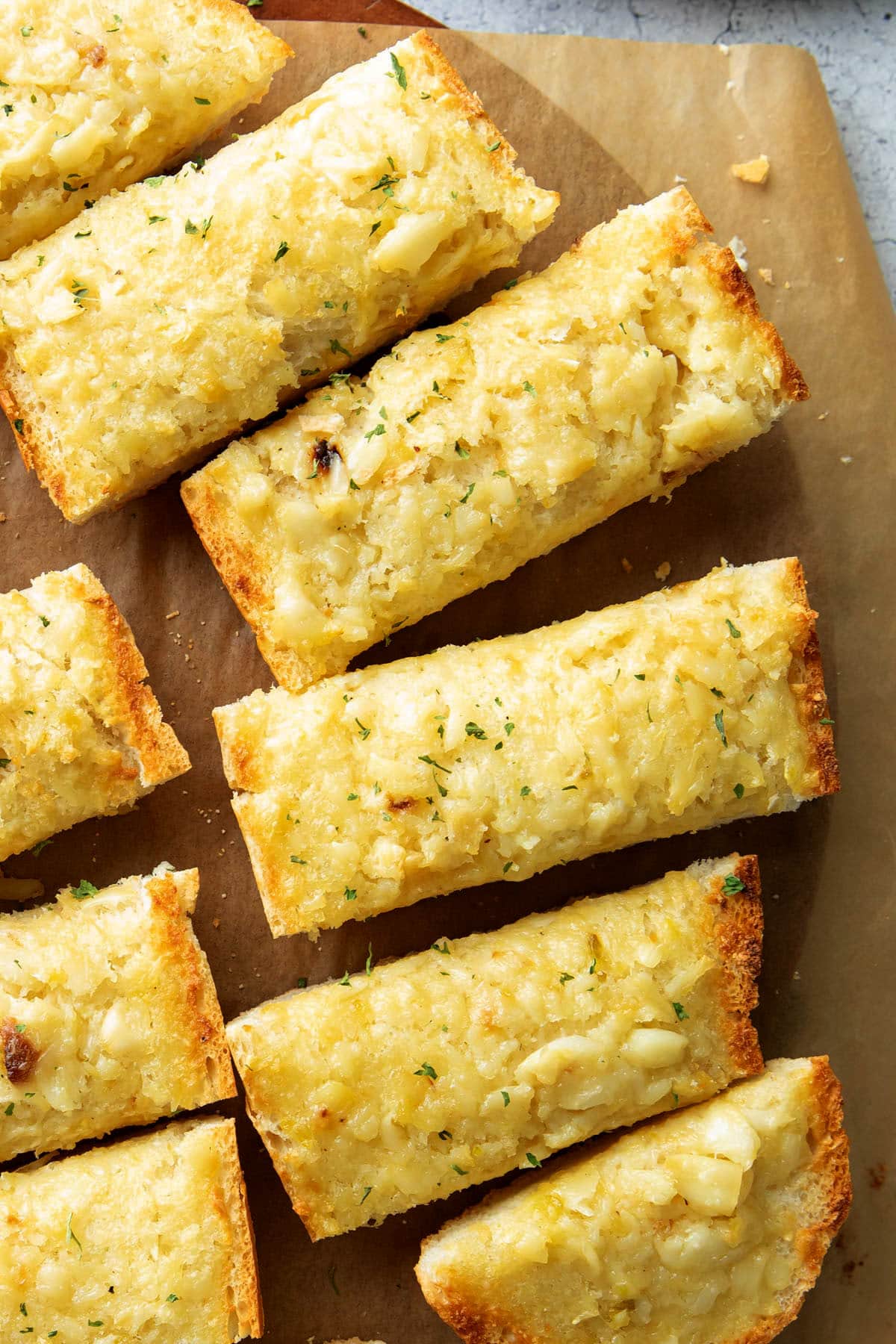 Close up of toasted edges and chunks of delicious garlic in butter on this roasted garlic garlic bread recipe.