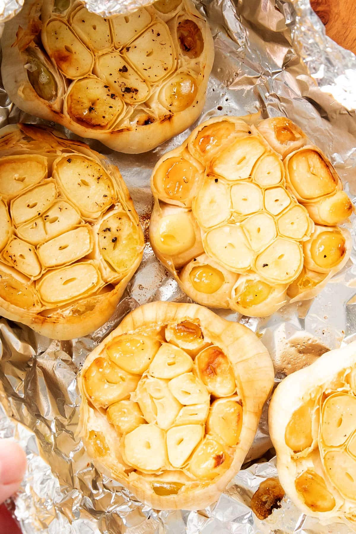 A photo showing how to make roasted garlic bread - close up of cloves of garlic roasted in foil packets.