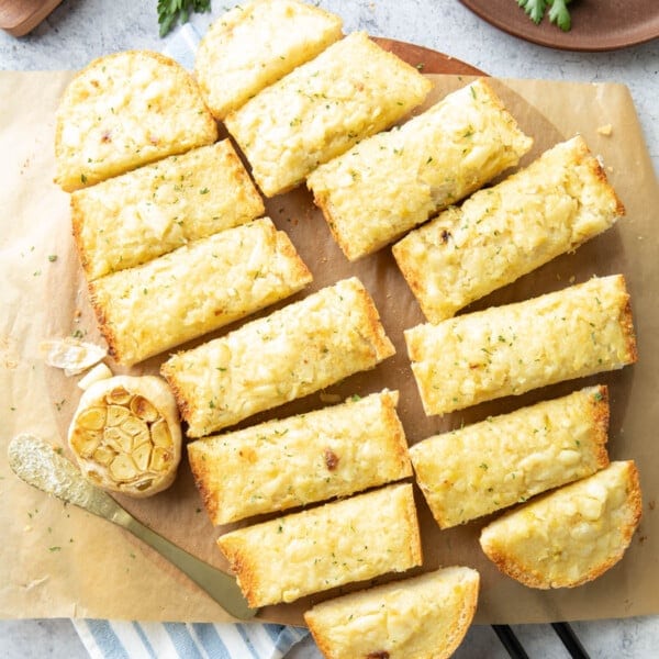 slices of roasted garlic bread on a parchment covered serving board