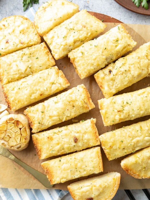 slices of roasted garlic bread on a parchment covered serving board