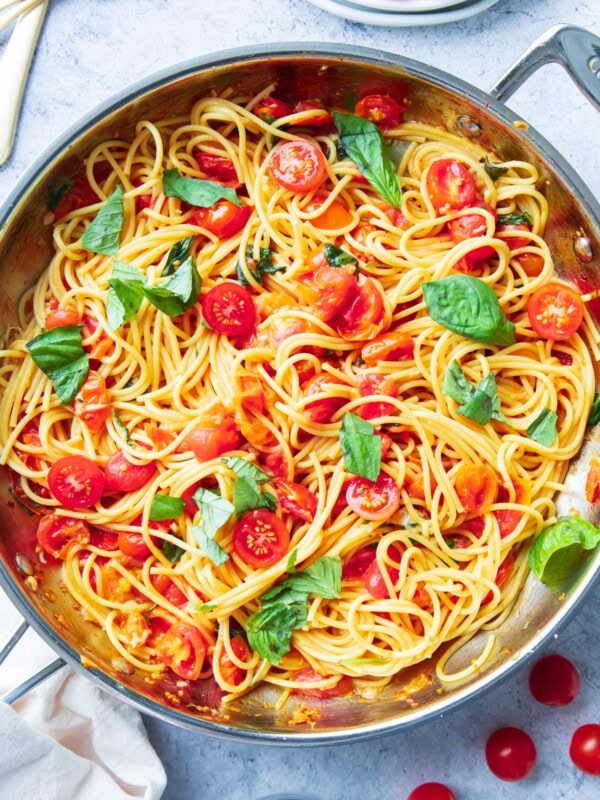 The finished Italian dinner recipe in a skillet with forks, plates, and a napkin for serving