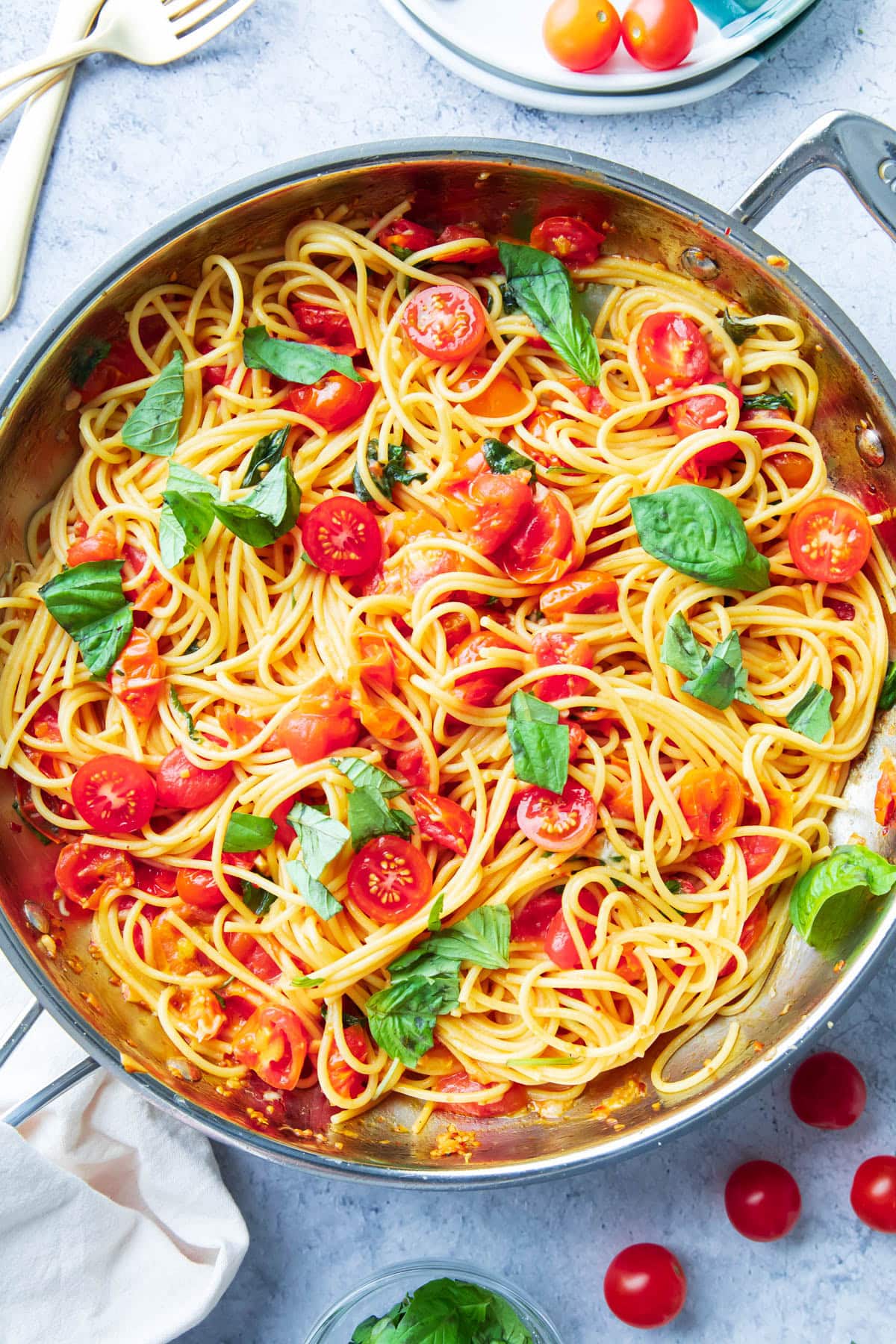 The finished Italian dinner recipe in a skillet with forks, plates, and a napkin for serving