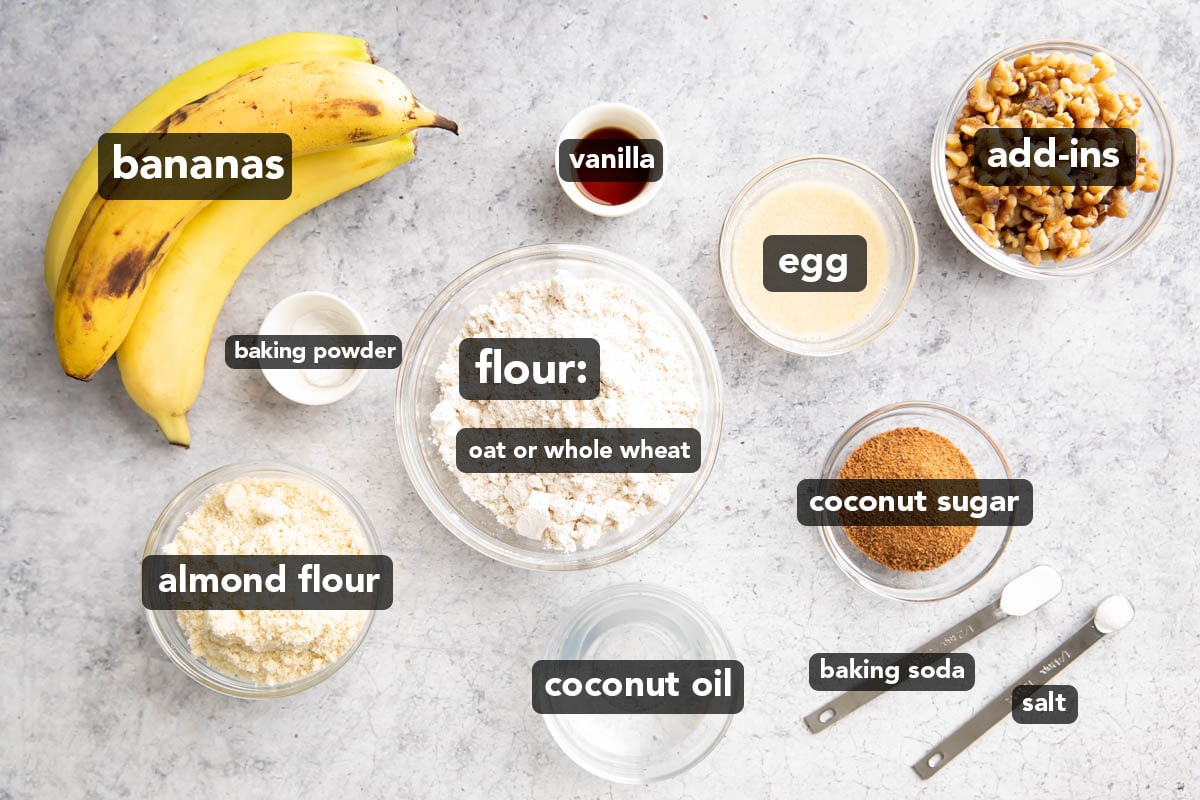 Zdrowe składniki muffinów bananowych ułożone na stole kuchennym, w tym banany, mąka, proszek do pieczenia, jajko, wanilia, cukier i inne