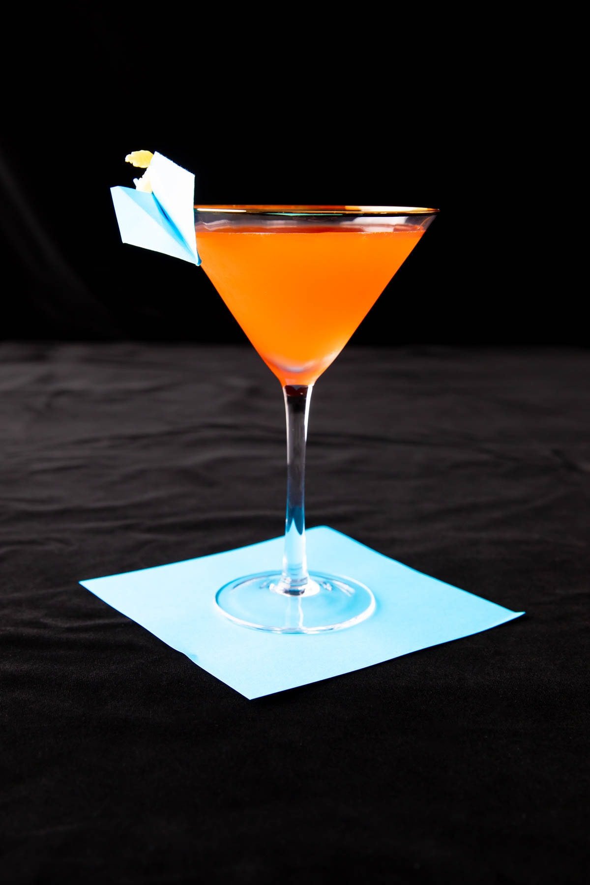 Paper Plane Cocktail served against a black backdrop