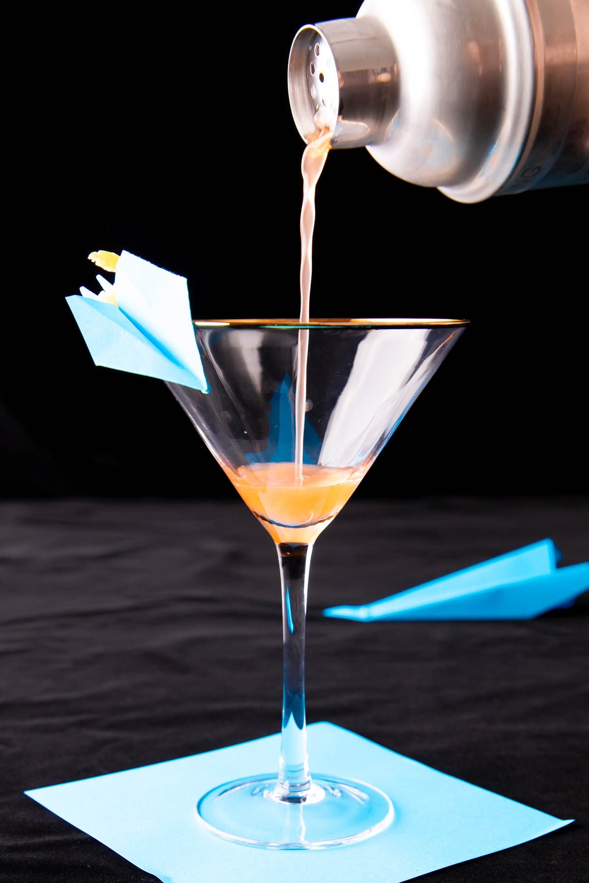 A photo showing How to Make a Paper Plane Cocktail – straining the cocktail mixture into a glass