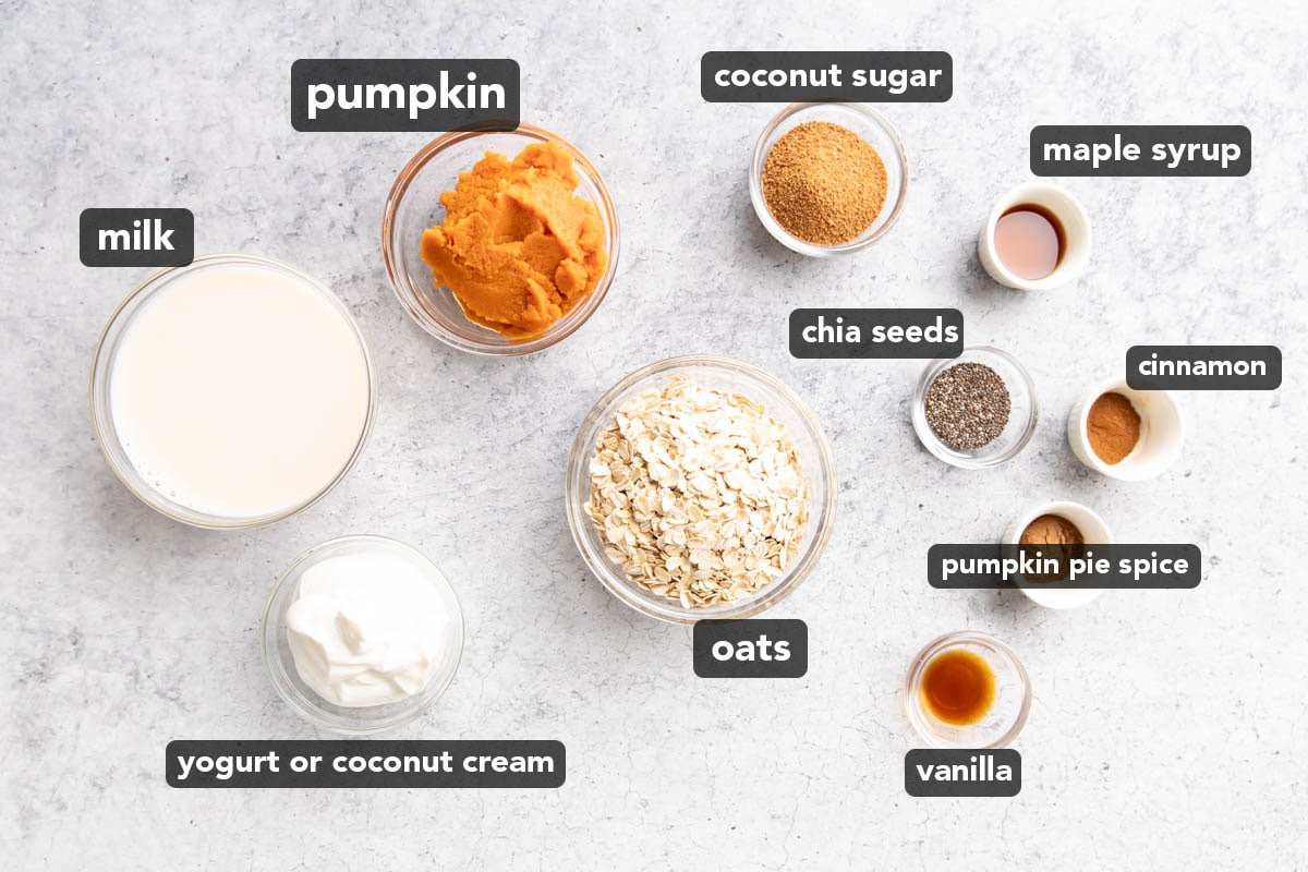 Pumpkin Overnight Oats Ingredients measured into small prep bowls, including oats, milk, pumpkin puree, chia seeds, spices, yogurt, and more