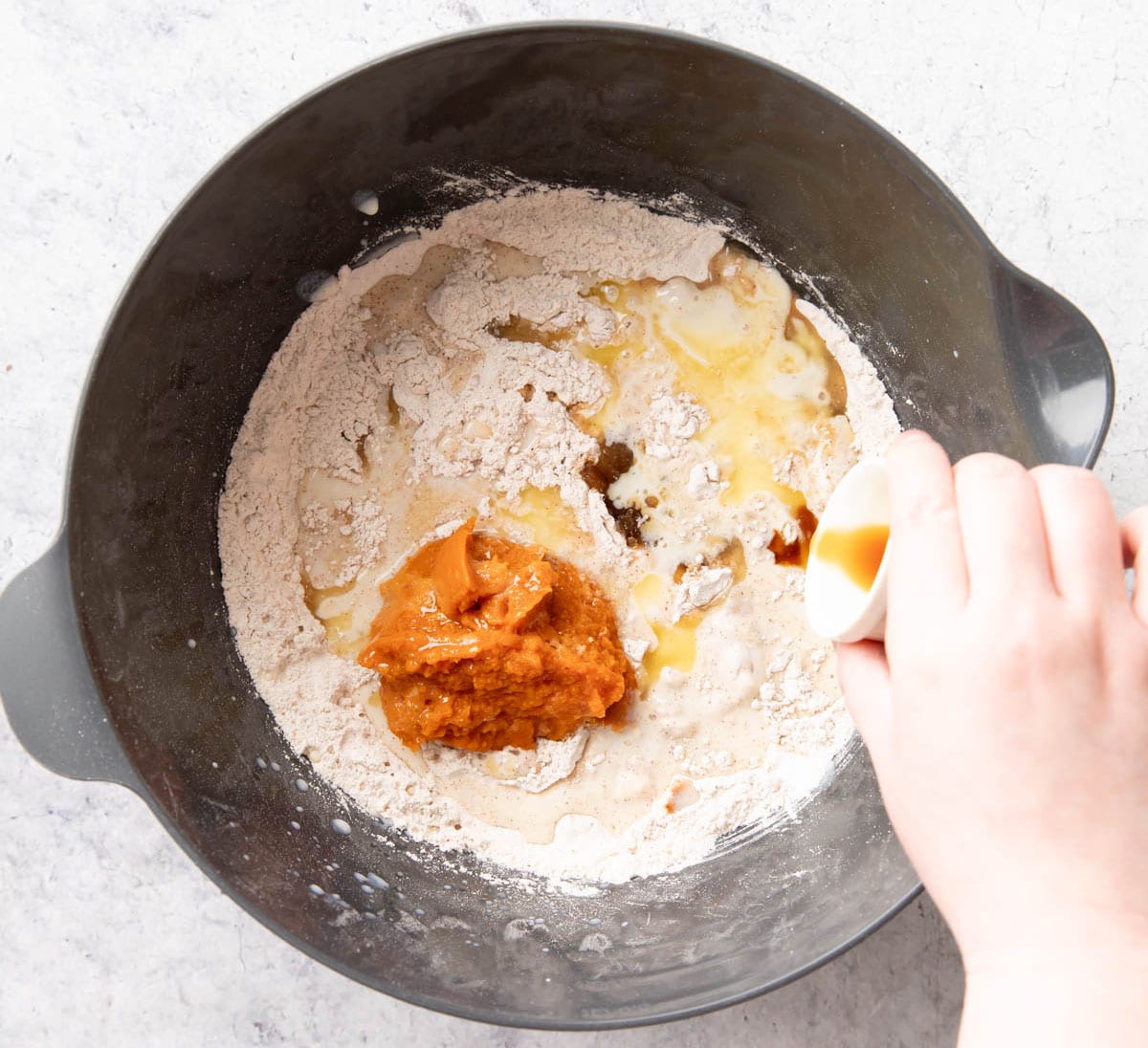 One photo showing How to Make Pumpkin Pancakes – adding the wet ingredients to the dry ingredients in the mixing bowl