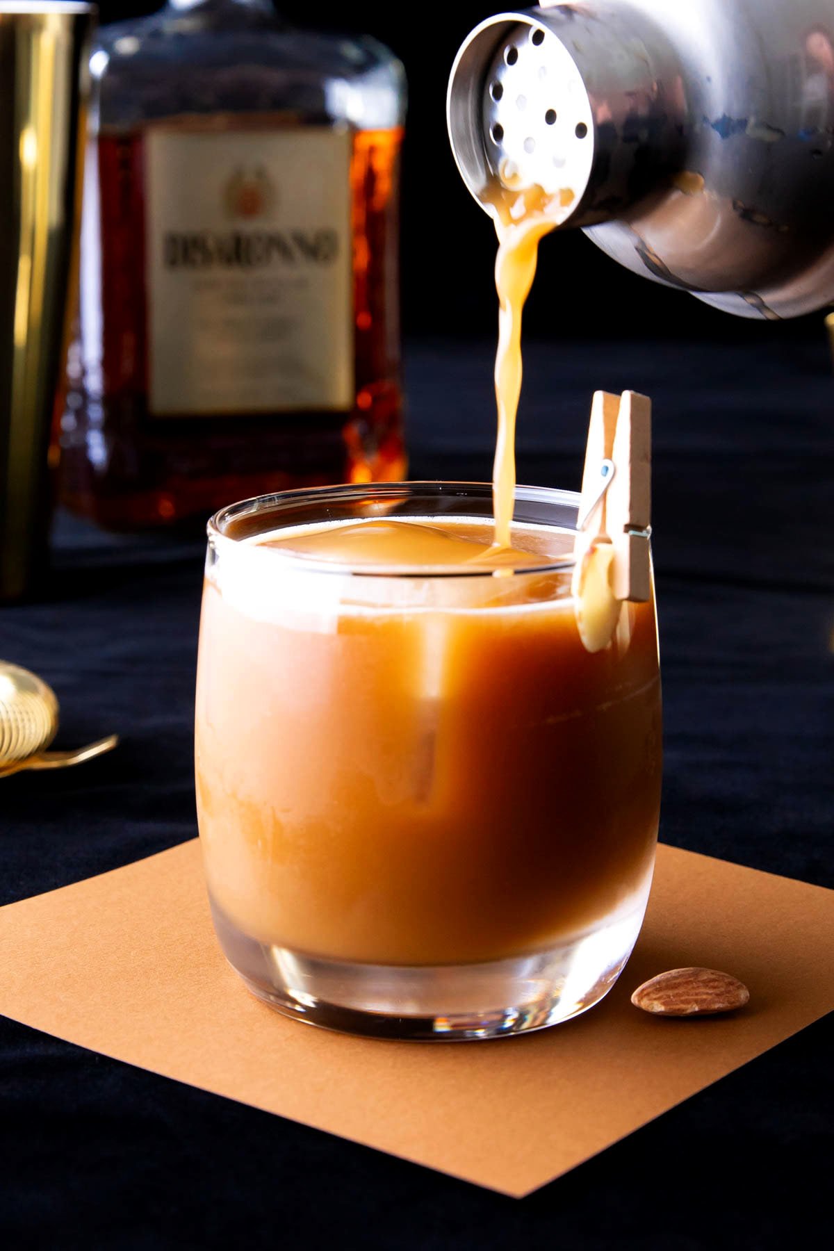 Someone pouring Toasted Almond cocktail into a cocktail glass with a garnish