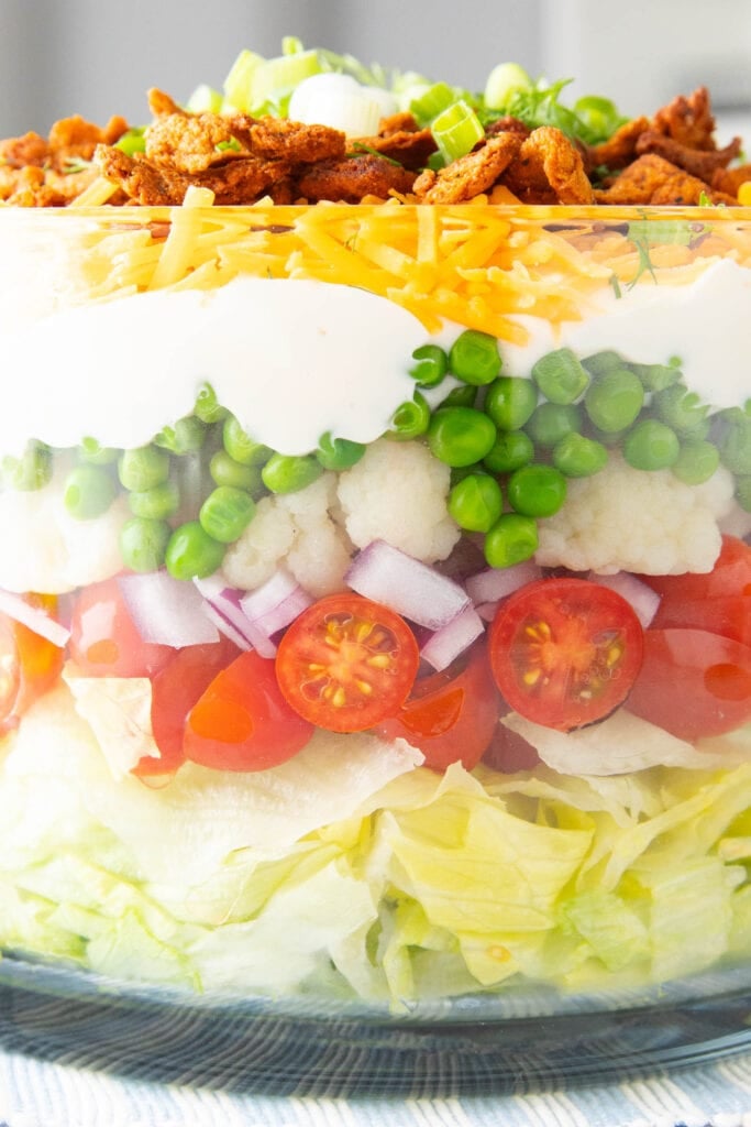 7 Layer Salad close up with peas, cauliflower, onions, lettuce, and tomatoes as layers