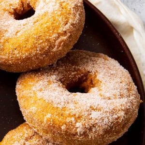 baked pumpkin donuts arranged on a plate are soft and moist with plenty of pumpkin spice flavor